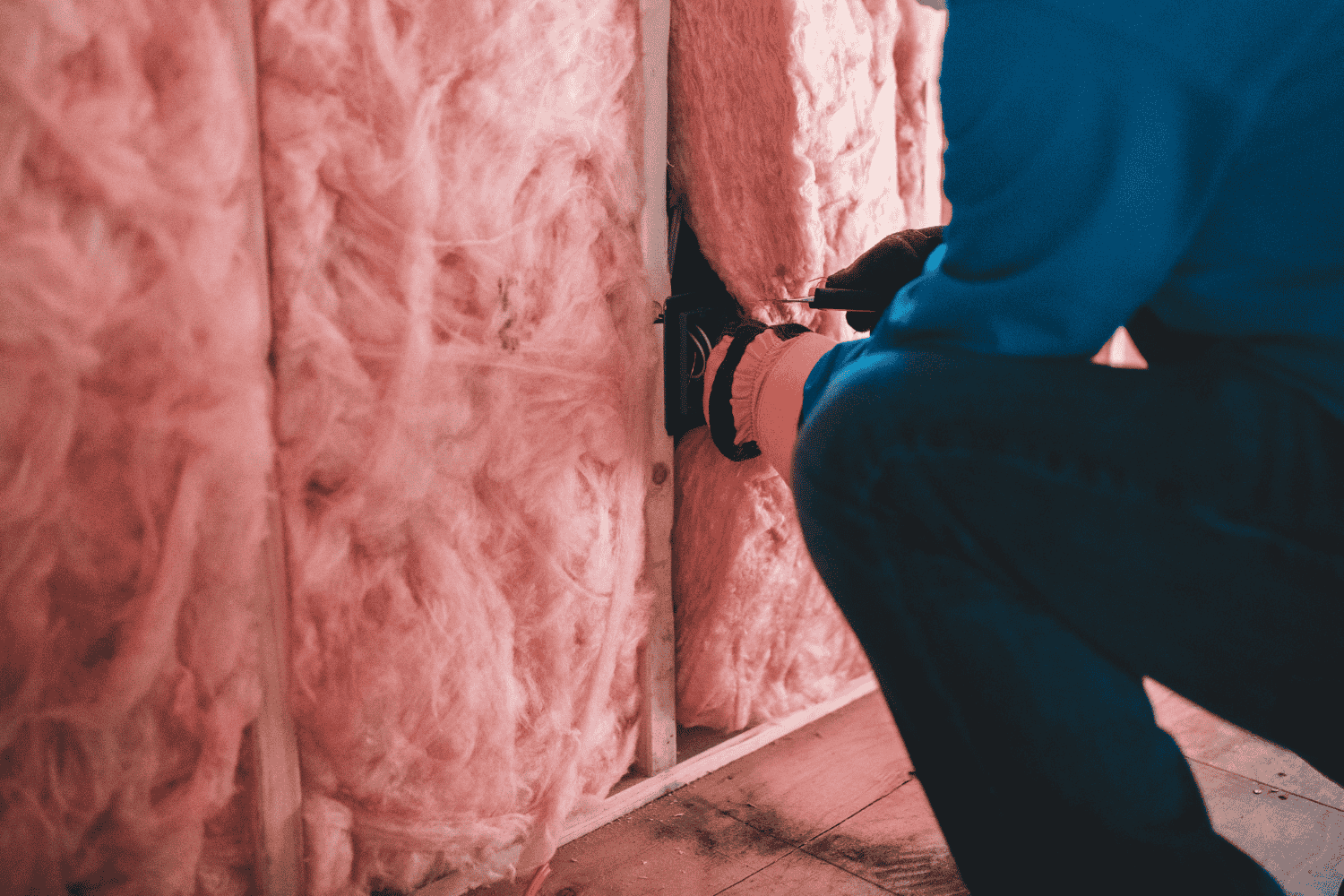 A person installing batt insulation in an attic.