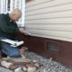 A professional foundation inspector examining a home's foundation.